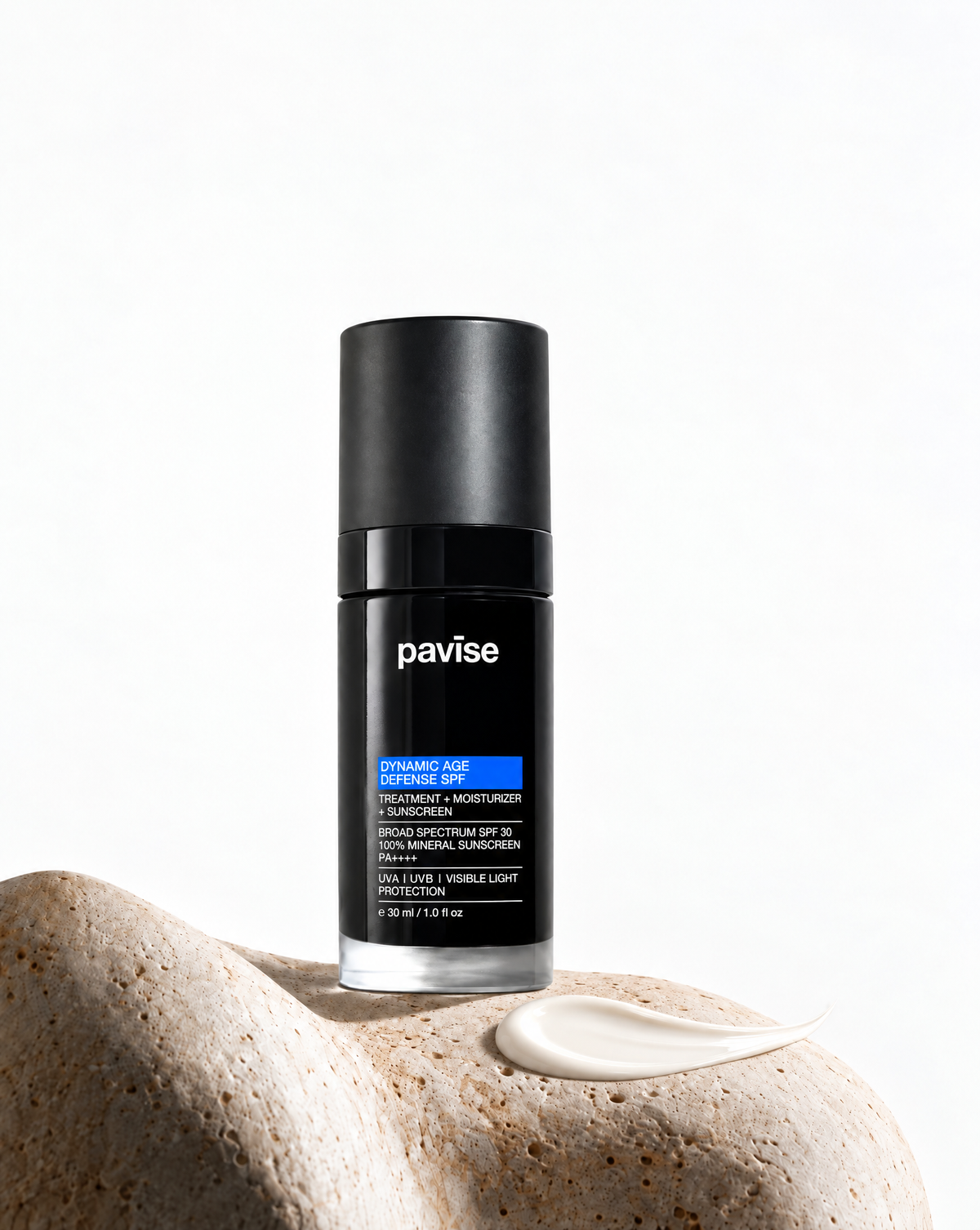Pavise Dynamic Age Defense bottle on stone beside a swipe of off-white mineral sunscreen