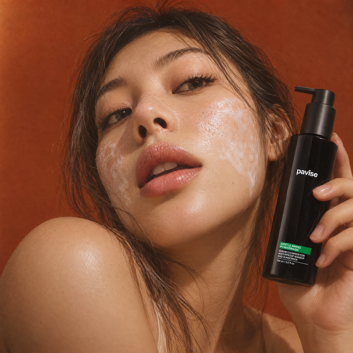 Woman with fine cleanser foam on her cheeks holding Pavise Gentle Amino Powerwash